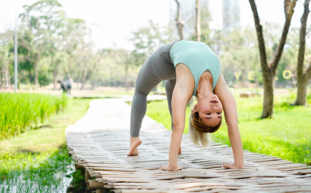 Junge asiatische Frau praktiziert Yoga im Garten.