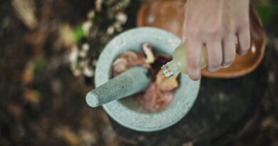 high angle photo of person pouring liquid from bottle inside mortar and pestle