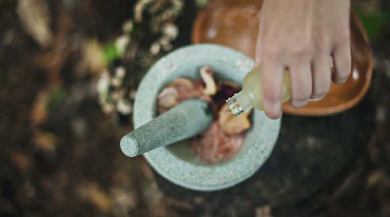 high angle photo of person pouring liquid from bottle inside mortar and pestle